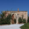 Stone bungalow with traditional wall and gate entrance into courtyard.
